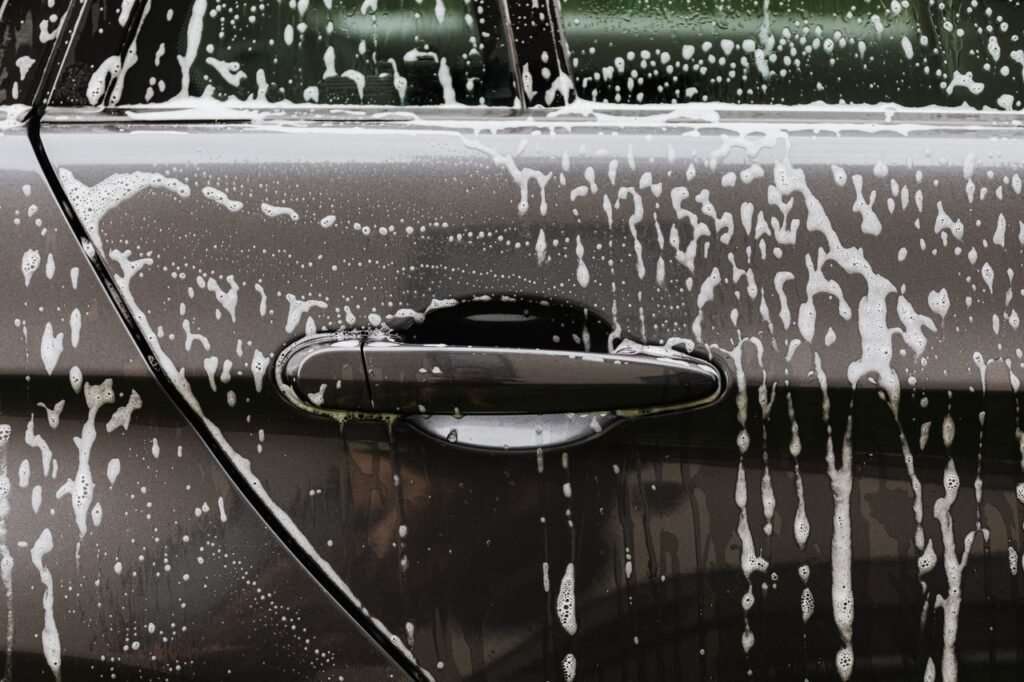 Mastering the First Impression: Your intriguing post title goes here Detailed close-up of soap suds on a black car door during a wash, highlighting automotive care.